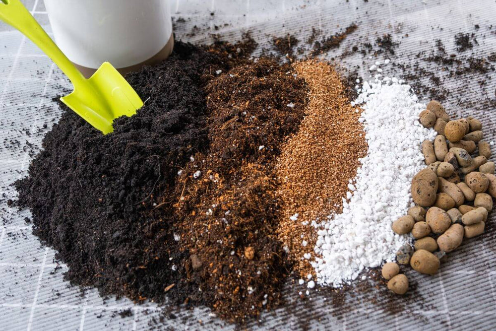 Different types of potting soil and additives laid out on a table with a green shovel